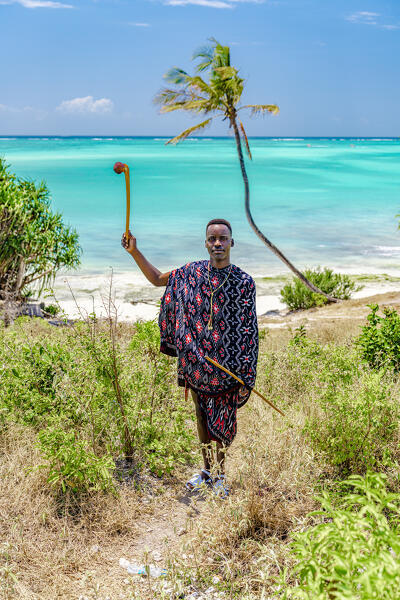 Portrait of young Maasai warrior holding a stick looking at camera, Zanzibar, Tanzania