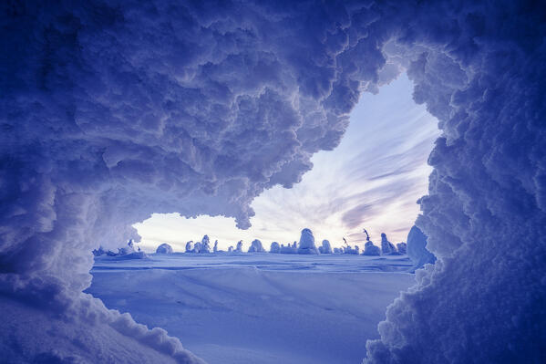Winter scenery at dusk view from opening of an ice cave in shape of a heart, Riisitunturi National Park, Posio, Lapland, Finland