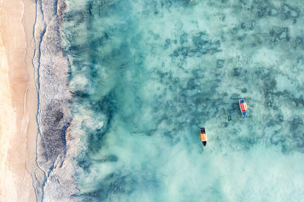 White sand beach washed by waves of the turquoise sea, overhead view, Zanzibar, Tanzania