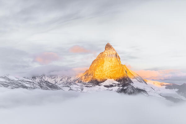 Matterhorn peak lit by sunrise on a foggy morning, Gornergrat, Zermatt, canton of Valais, Switzerland