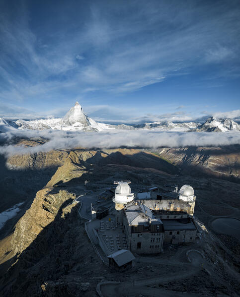 Foggy sunrise over Matterhorn peak and Kulmhotel Gornergrat, aerial view, Zermatt, Valais canton, Switzerland