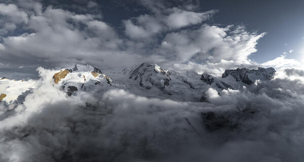 Clouds over Monte Rosa, Lyskamm, Pollux, Castor, Breithorn peaks emerging  from fog, aerial view, Zermatt, Valais, Switzerland