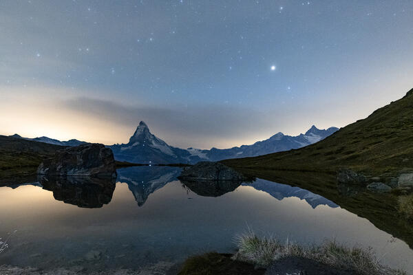 Matterhorn peak reflected in lake Stellisse under the glowing stars at night, Zermatt, Valais canton, Switzerland