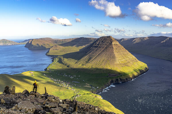 High angle view of hiker with backpack admiring a fjord standing on mountain peak in summer, Vidareidi, Vidoy Island, Faroe Islands (MR)