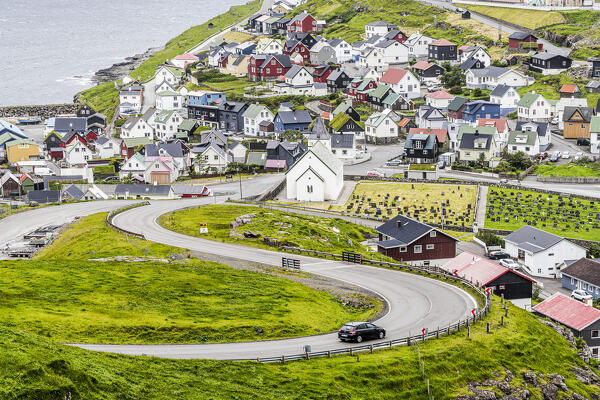 High angle view of car driving on winding road to the iconic Eidi village, Eysturoy Island, Faroe Islands