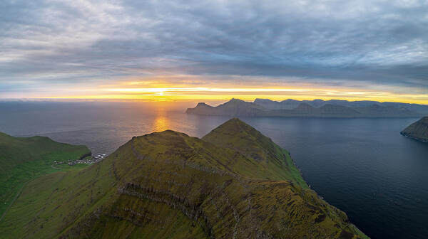 Dramatic sky at dawn over Gjogv and majestic cliffs along Funningur fjord, Eysturoy Island, Faroe Islands