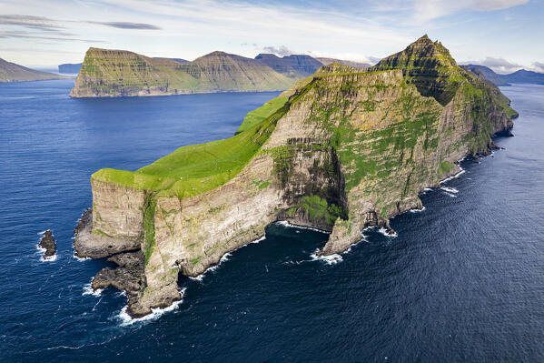 Panoramic aerial view of Kallur lighthouse with Borgarin and Nestindar mountain above the ocean, Kalsoy island, Faroe Islands