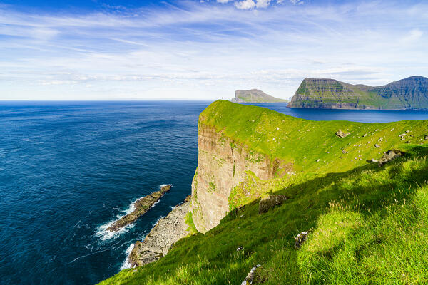 Green meadows on majestic cliffs with Kallur lighthouse overlooking the Atlantic Ocean, Kalsoy island, Faroe Islands, Denmark