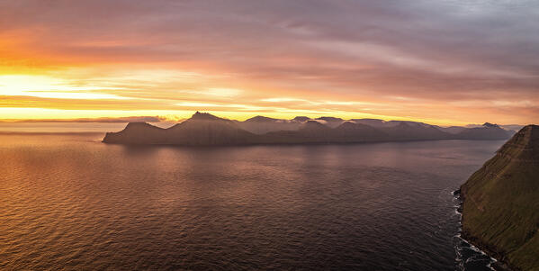 Burning sky at dawn over Kalsoy island and the calm water of a fjord, Gjogv, Eysturoy Island, Faroe Islands