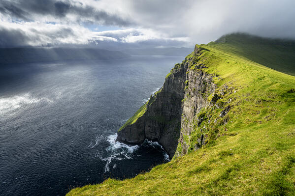 Sun rays through clouds in the scenic sky over the ocean view from cliffs, Nordradalur, Streymoy Island, Faroe Islands
