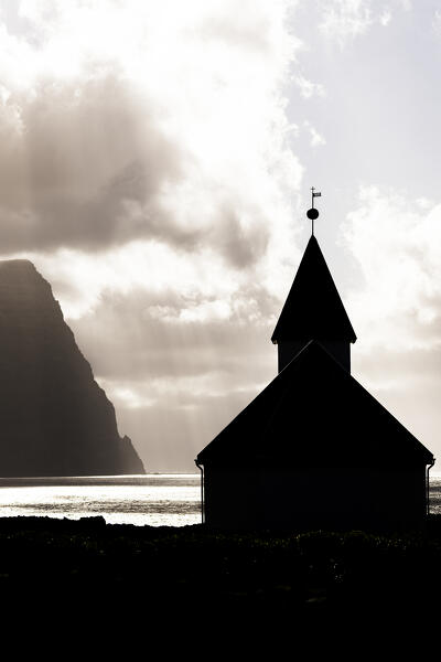 Silhouette of Vidareidi church under a dramatic sky with clouds in summer, Vidoy Island, Faroe Islands