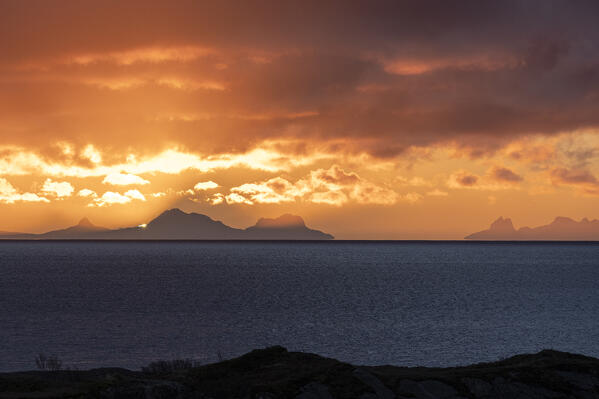 Burning sky at sunrise over mountains ovelooking the cold sea, Reine, Lofoten Islands, Norway