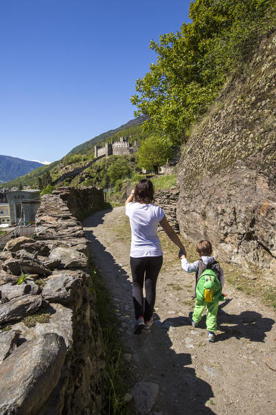 Mother accompanies her son down the path that leads to Castle Visconti Venosta. Grosio. Valtellina. Lombardy. Italy. Europe