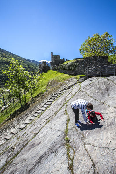 Tourists observe the rock carvings of Rupe Magna near the Castle Visconti Venosta in Grosio. Province of Sondrio. Valtellina. Lombardy. Italy. Europe