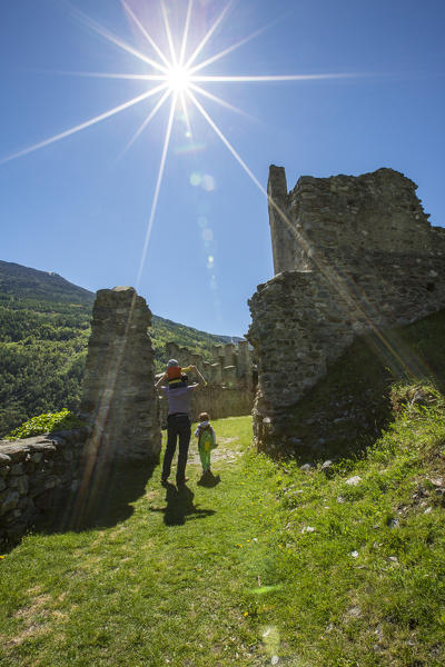 Tourists walk among the ruins of Castle Visconti Venosta. Grosio. Province of Sondrio. Valtellina. Lombardy. Italy. Europe