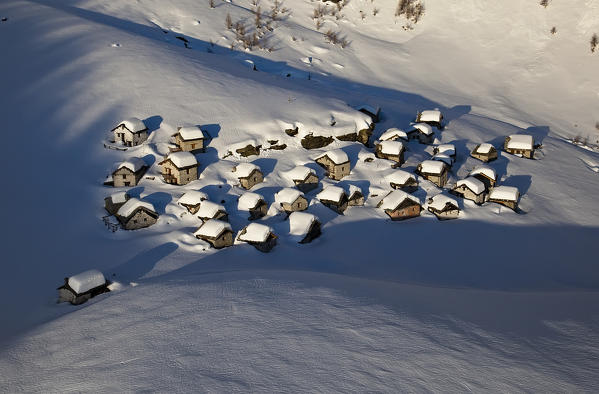 Aerial view of mountain huts of Lendine Alp after a heavy winter snowfall. Valchiavenna. Valtellina. Lombardy. Italy. Europe. 