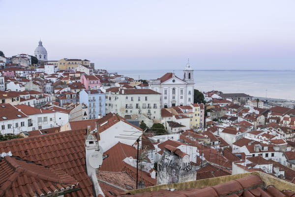 View of terracotta roofs and the ancient dome from Miradouro Alfama viewpoint at dusk Lisbon Portugal Europe