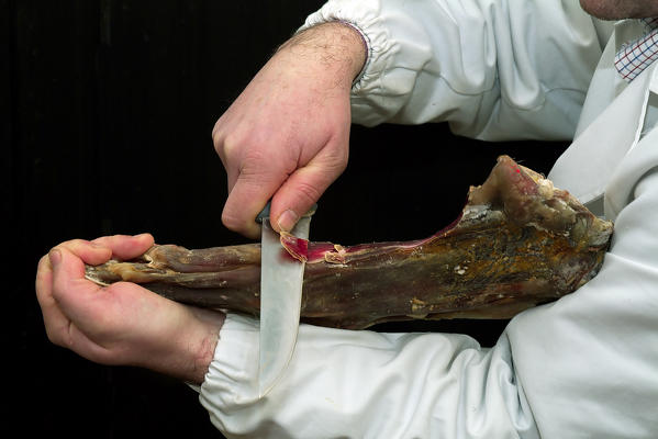 A violino di capra from Valchiavenna cut by expert hands. Made from the legs or shoulders of goats, this unusual cured meat is actually shaped like a violin, the mass of muscle tapering down to the hoof like the neck of the musical instrument. It is typical throughout the Valchiavenna, Lombardy Italy Europe