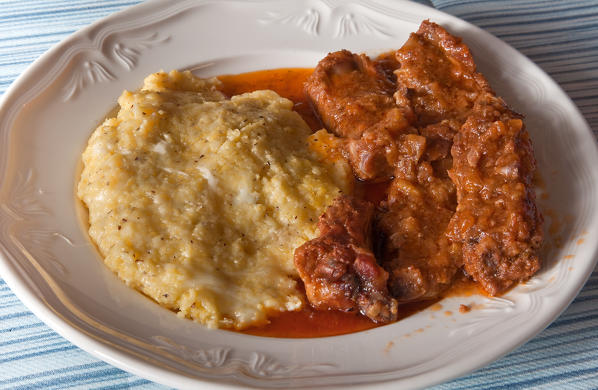 Polenta Taragna, typical of Valtellina, and its dark color, due to the use of buckwheat flour (mixed with cornmeal), containing substantial amounts of butter and cheese, served with ribs cooked in a lavec, a typical pot. Lombardy Italy Europe