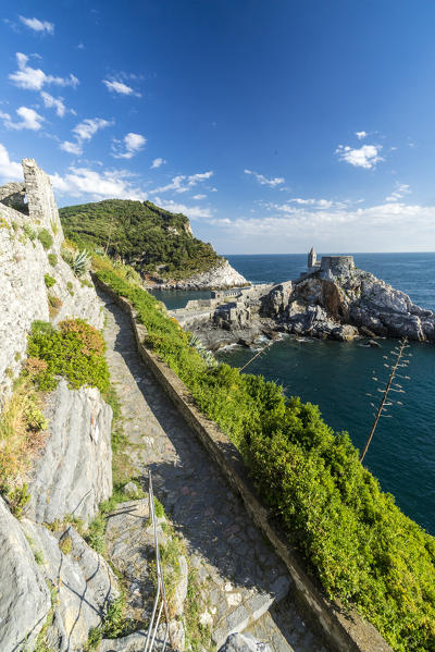 Green plants frame the old castle and  church perched on the promontory Portovenere province of La Spezia Liguria Italy Europe