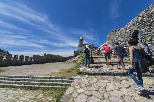 Tourists beside the medieval wall that leads to old castle and church Portovenere province of La Spezia Liguria Italy Europe