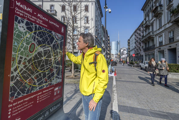 A tourist looks at the map for the walking routes in town Milan Lombardy Italy Europe
