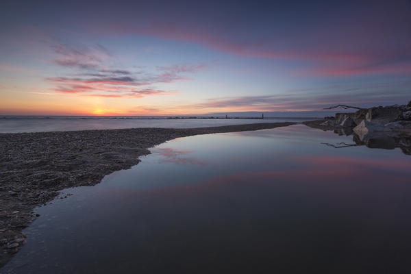 Pink sky is reflected in the clear water at dawn Porto Recanati Province of Macerata Conero Riviera Marche Italy Europe