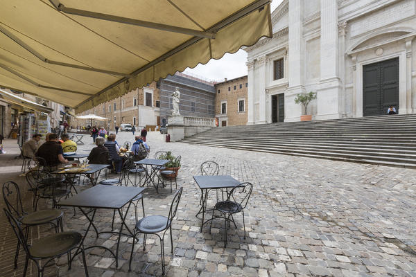 Typical cafe frames the flight of steps of the marble facade of ancient Duomo Urbino Province of Pesaro Marche Italy Europe