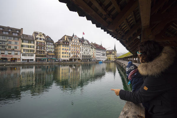 Tourists on Chapel Bridge admire the typical buildings of the old town on river Reuss Rathausquai Lucerne Switzerland Europe