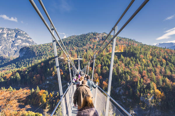 Tourists on the suspension bridge called Highline 179 framed by colorful woods in autumn Ehrenberg Castle Reutte Austria Europe