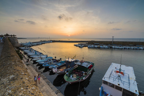 Sunset lights on boats moored in the harbor surrounded by medieval walls Gallipoli province of Lecce Apulia Italy Europe