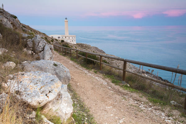 Pink sky on turquoise sea frames the lighthouse at Punta Palascia at sunset Otranto province of Lecce Apulia Italy Europe