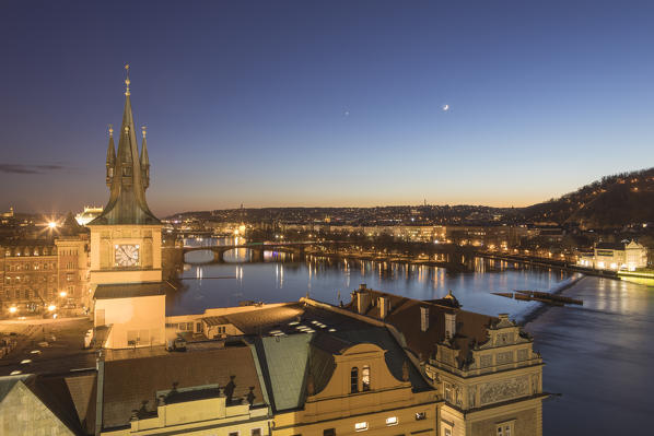 Vltava (Moldava) river framed by the clock tower and ancient bridges at dusk Prague Czech Republic Europe
