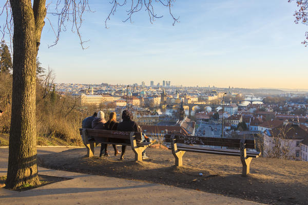 People on a bench admire the historical buildings  and bridges on Vltava (Moldava) river at sunset Prague Czech Republic Europe