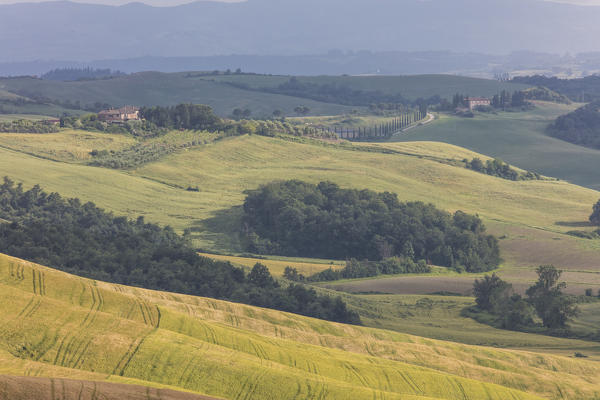 Green rolling hills and farm houses of Crete Senesi (Senese Clays) province of Siena Tuscany Italy Europe