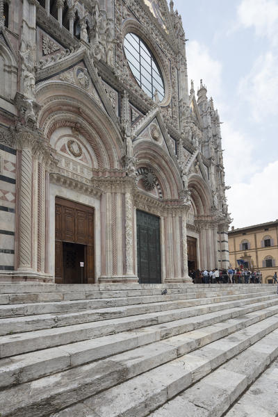 The ancient flight of steps and artistic sculptures of the facade of the historic Cathedral of Siena Tuscany Italy Europe