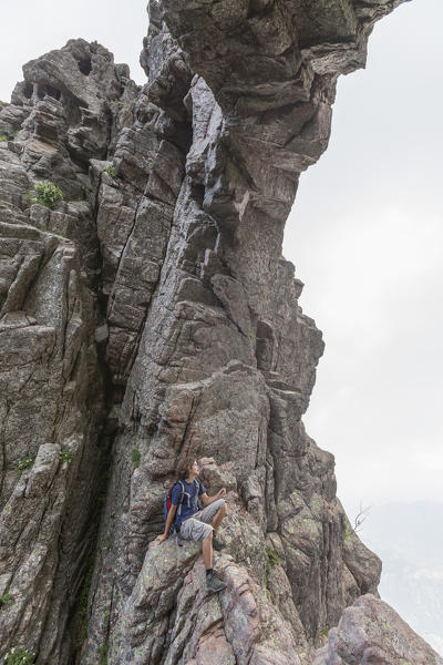 Hiker sits on the rocks of the natural arch Col de Bavella (Pass of Bavella) Solenzara Southern Corsica France Europe
