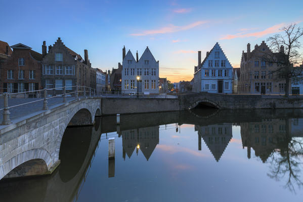 Dusk lights on the historic buildings of the city centre reflected in the typical canals Bruges West Flanders Belgium Europe