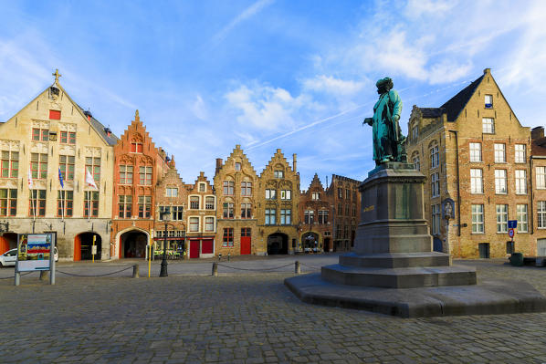 Old statue in the medieval square framed by the typical houses and buildings at dawn Bruges West Flanders Belgium Europe