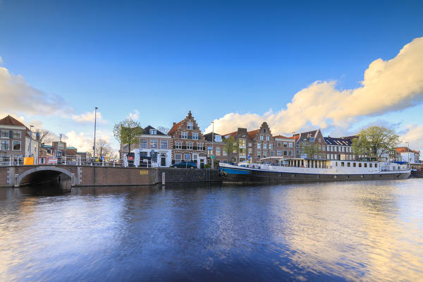 Blue sky and clouds on typical houses reflected in the canal of the river Spaarne Haarlem North Holland The Netherlands Europe