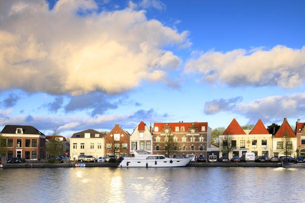 Blue sky and clouds on typical houses reflected in the canal of the river Spaarne Haarlem North Holland The Netherlands Europe