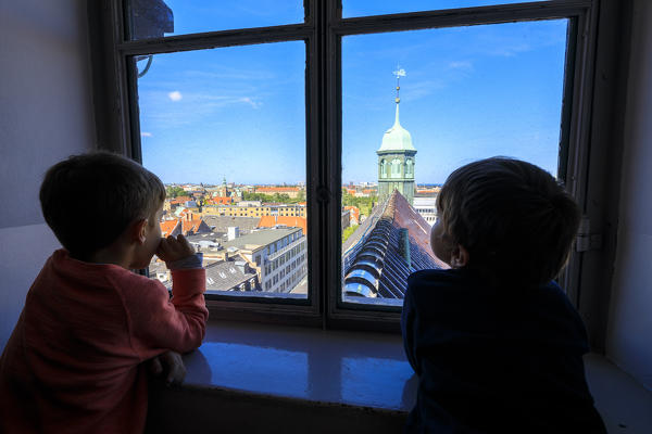 Two child look the Trinitatis Church from a window inside the Round Tower (Rundetaarn), Copenhagen, Denmark