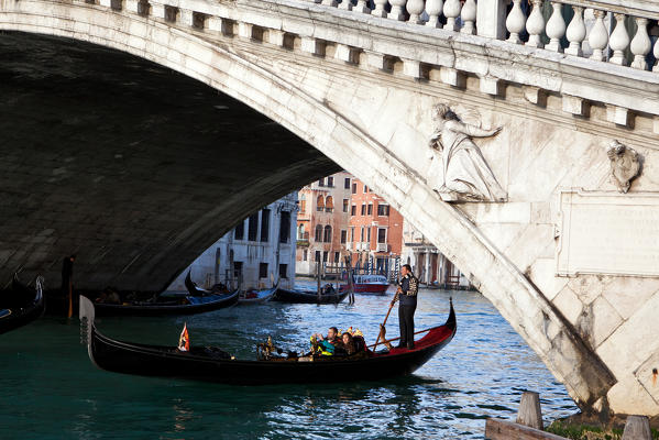 A gondola riding along Grand Canal under the Rialto bridge in Venice, Veneto Italy Europe