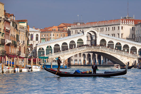 A gondola crossing the Grand Canal right in front of the Rialto Bridge, one of the most recognizable Venetian landmarks  Venice, Veneto Italy Europe