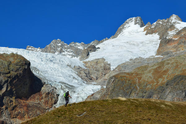 Trekker in Ferret Valley (Val Ferret) with Mont Dolent and Pré de Bar glacier on background, Ferret Valley, Aosta Valley,Italy,