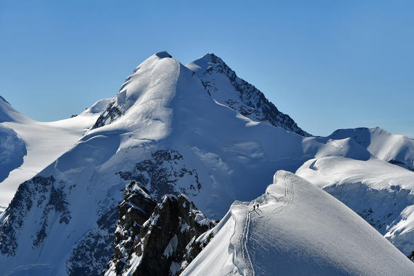 Mountaineers climbing Breithorn Centrale from Breithorn Occidentale, Lyskamm on background, Aosta Valley, Italy, Europe