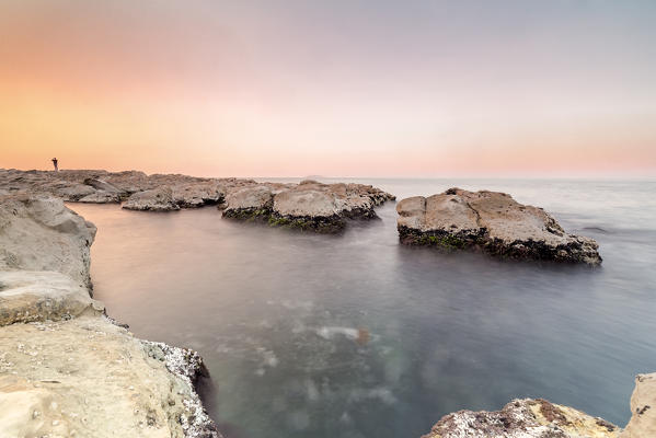 Boy over the rocks in Passetto coast at sunset, Ancona,Marche,Italy