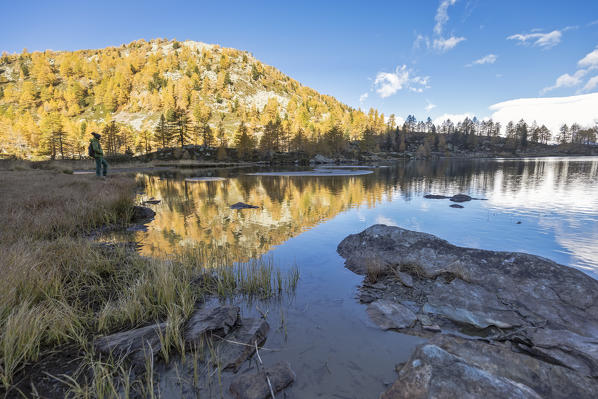 Hiker admires sunrise at Arpy Lake in autumn, Morgex, Aosta Valley, Italy, Europe