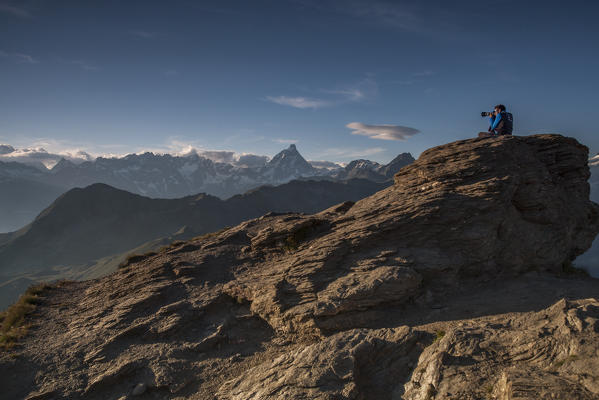 Photographer who photographs alpin landscape at sunset on the top of Monte Zerbion, Aosta Valley, Italy