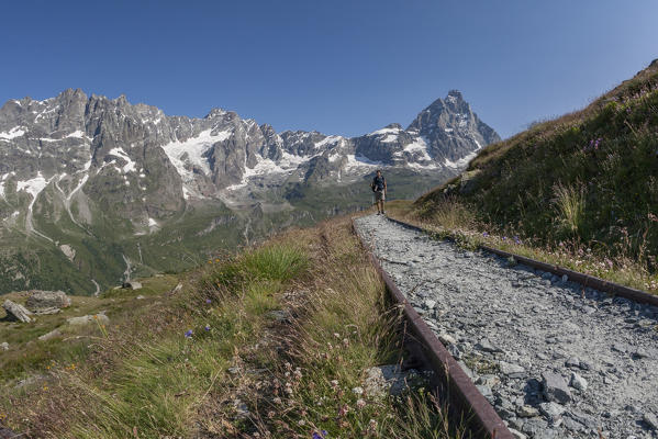 Hiker walking along the rails of the old train, Cervinia, Aosta Valley, Italy
